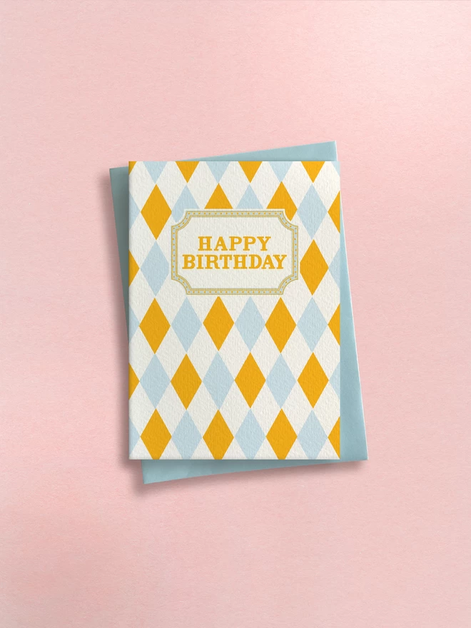 Greeting card designed by Flora Fricker in Bristol, UK. Happy Birthday harlequin pattern in yellow and blue. Gender neutral birthday card
