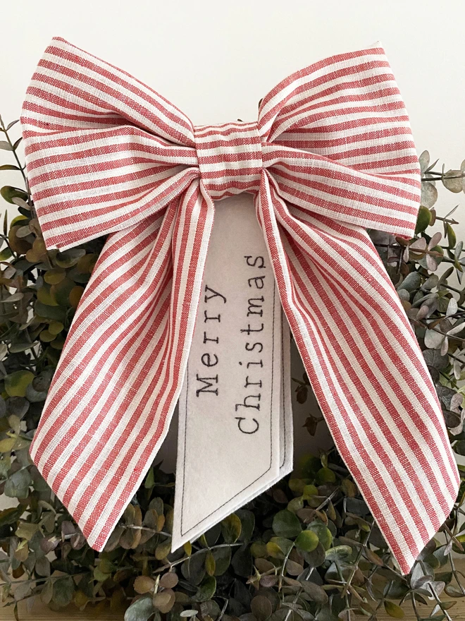 red stripe bow christmas wreath decoration with merry christmas words shown on a wreath