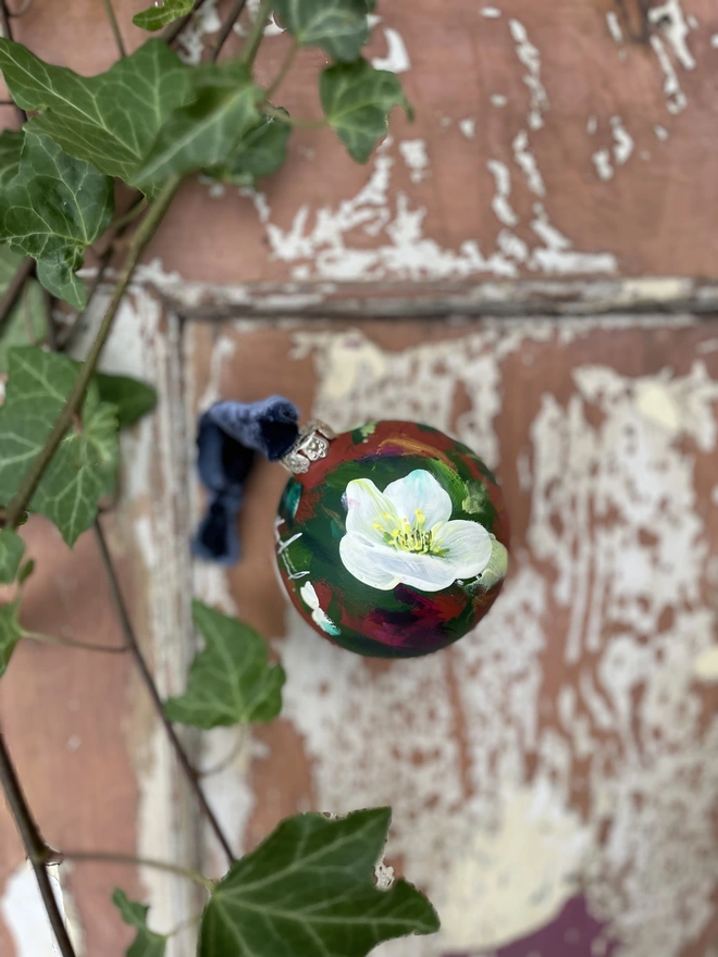 Hand painted floral ceramic bauble hellebores on a terracotta background 