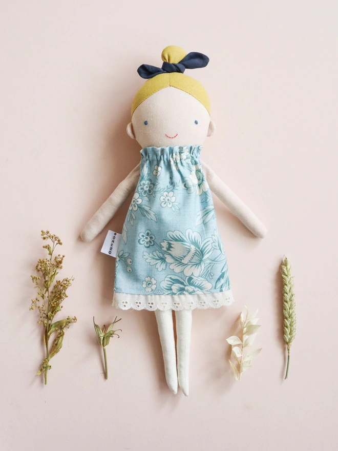 Cotton and linen doll with fair skin and blonde hair, wearing vintage inspired flower print in blue.