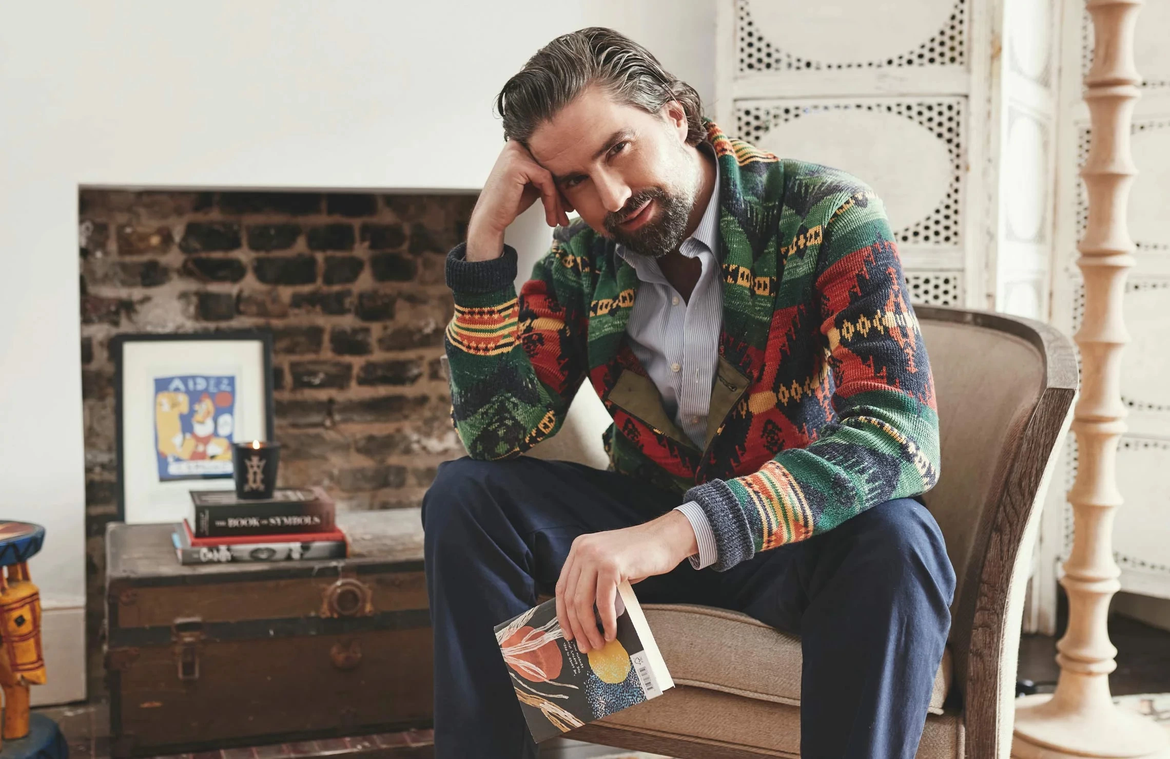 Jack Guinnes, writer, model, presenter and founder of The Queer Bible, looking at the camera, holding a book in his hand.