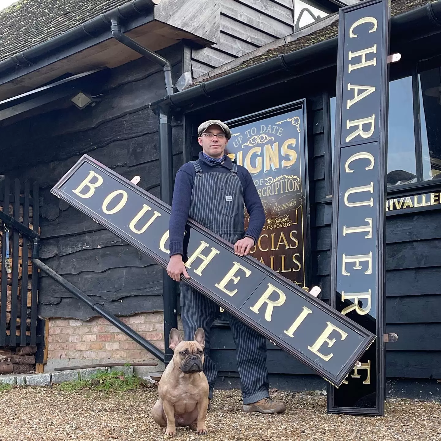 Ash Bishop, founder of The Brilliant Sign Company, holding a sign with his dog at his feet.