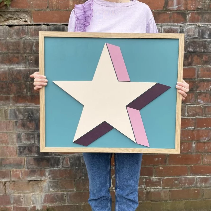 Woman holding a picture frame with a star print in it. 