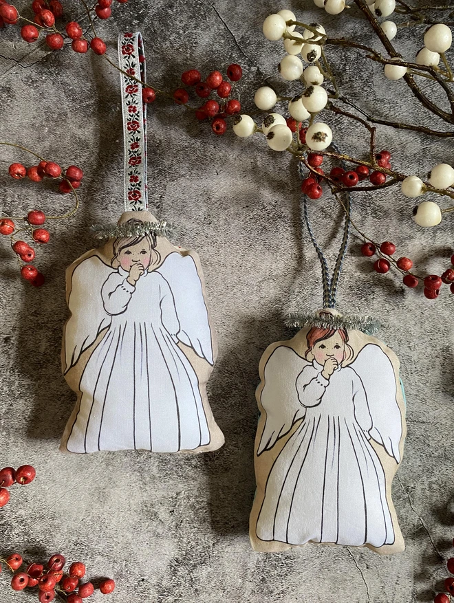 2 angel decorations for your Christmas tree made from fabric stuffed with hanging ribbons and angels are sucking their thumbs