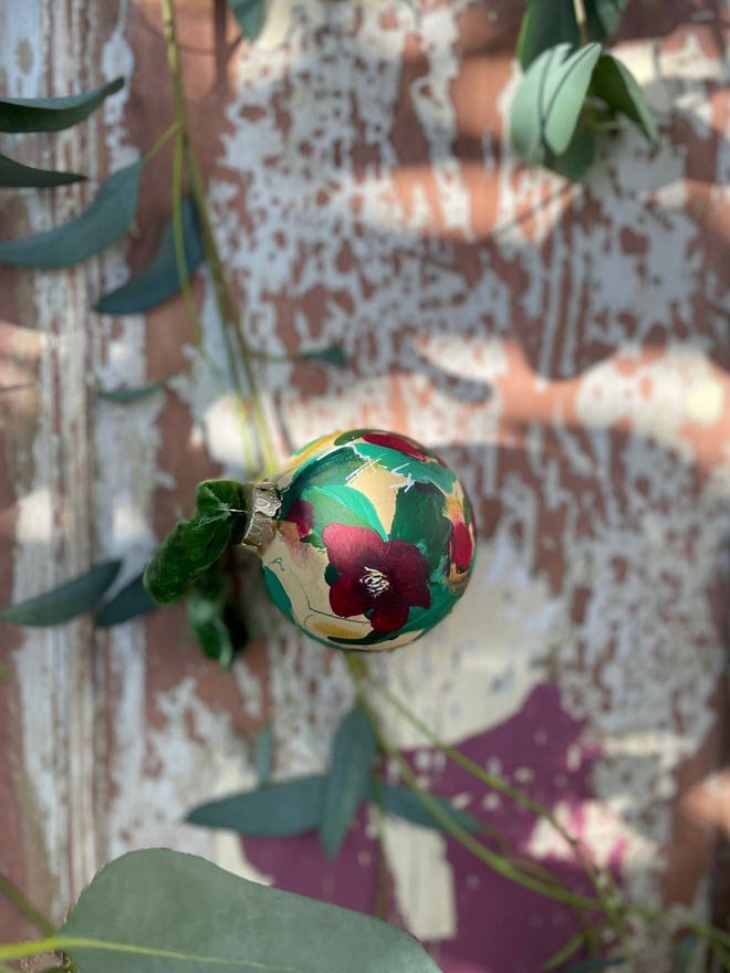 hand painted floral Christmas bauble dark cream background adorned with deep red hellebore flowers