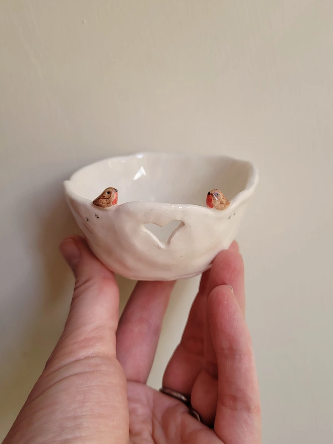 hand made ceramic tea light candle holder with a tiny robin couple, heart cut out and bird prints held in a hand