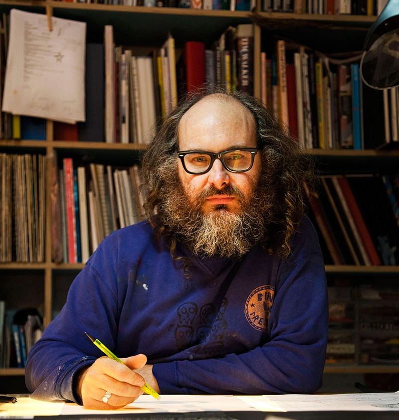 Rob Ryan, artist, looking at the camera in a blue jumper.