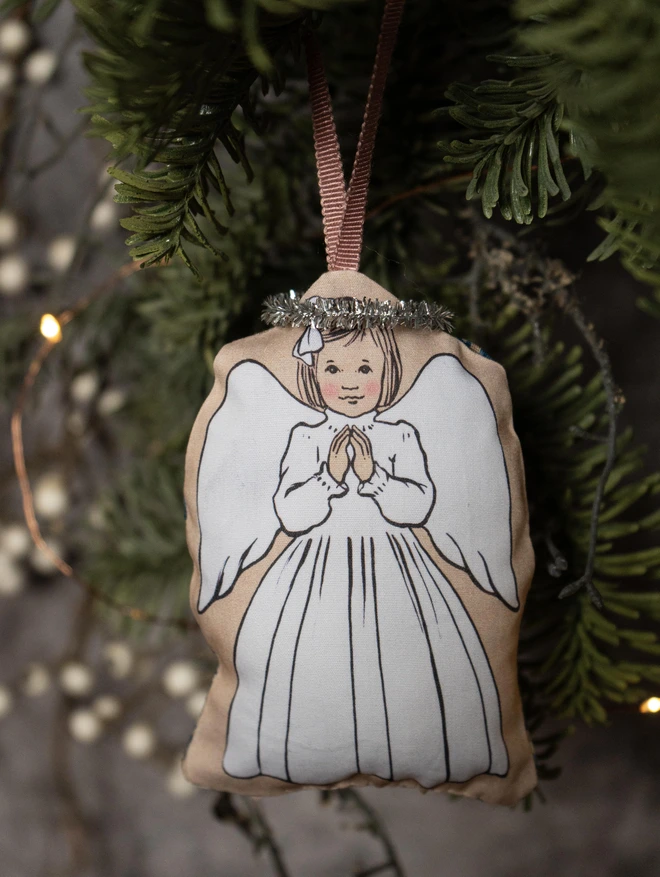 Christmas tree decoration of an angel praying hung with a ribbon in a Christmas tree