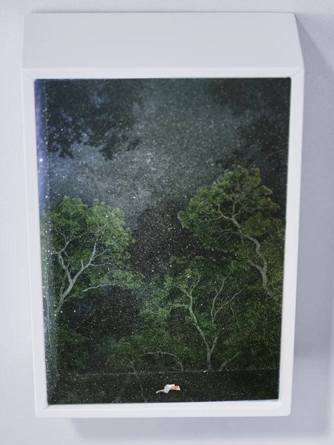 Miniature scene in an artbox showing a tiny woman sleeping in a sparkling night forest