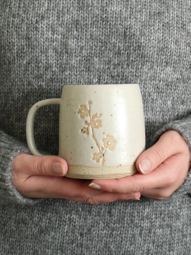 Hands holding cherry blossom mug