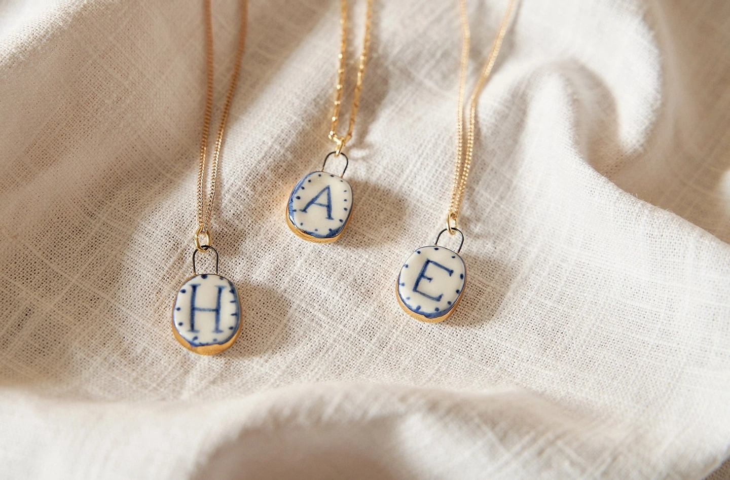 Ceramic initial pendant. Ceramic charms with an initial in blue paint on a gold chain