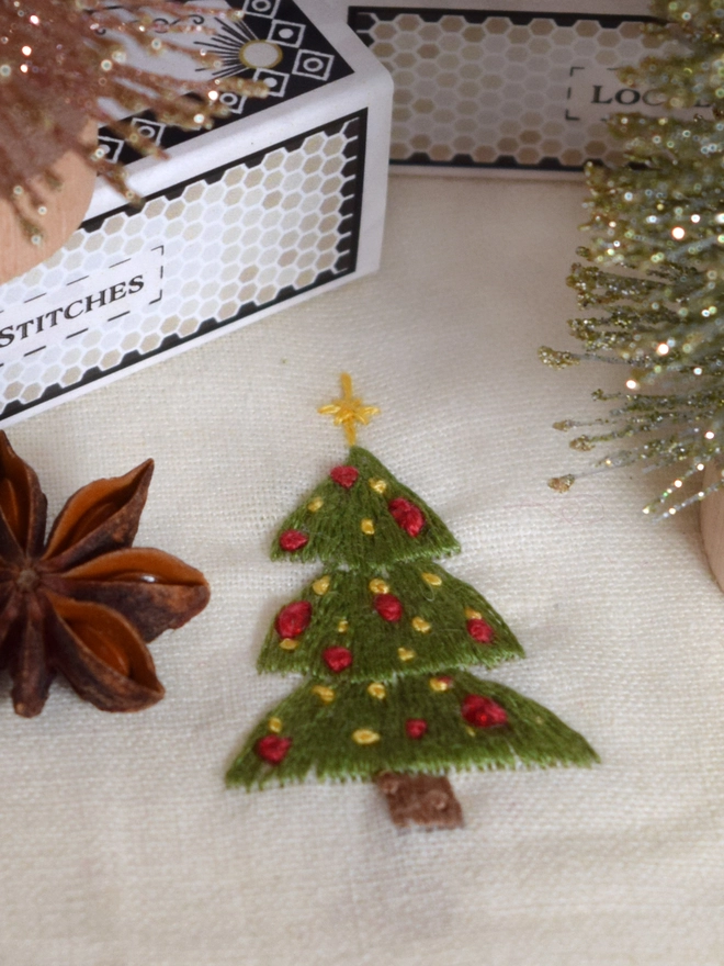 A bright green Christmas tree, with yellow star, mini baubles in red & yellow and 3 red crystal baubles.