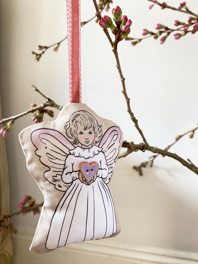 pretty fairy with lilac wings hung on blossom branch holding a lilac heart button