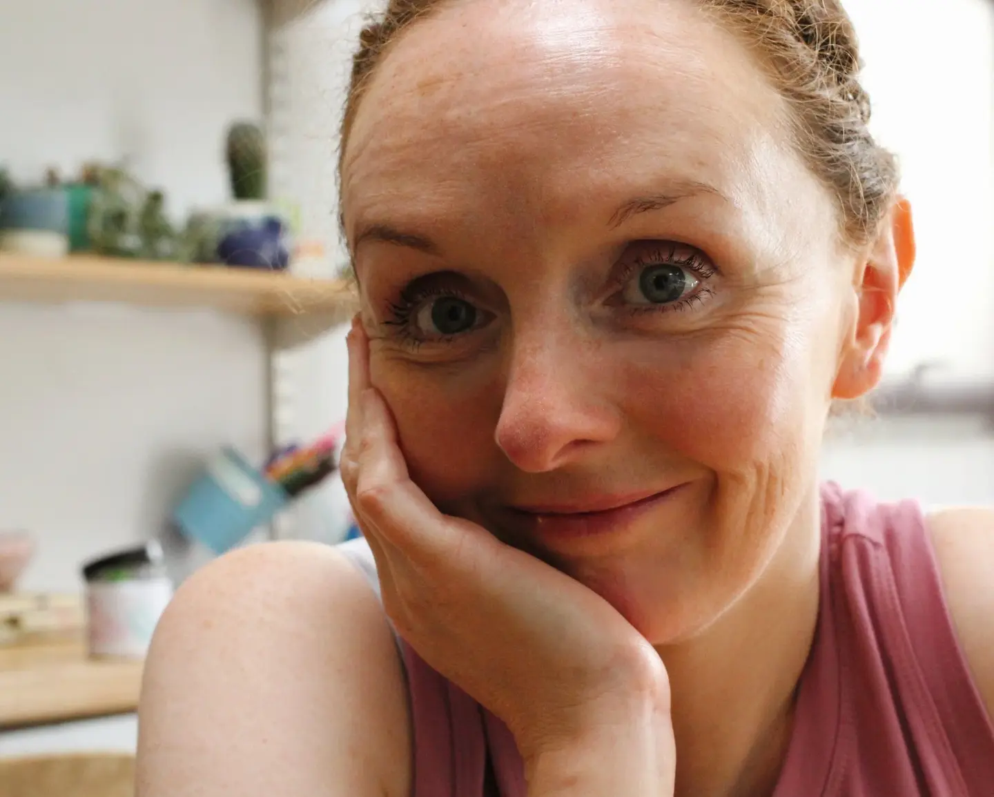 Gillian smiling into the camera, with her head resting in her hand