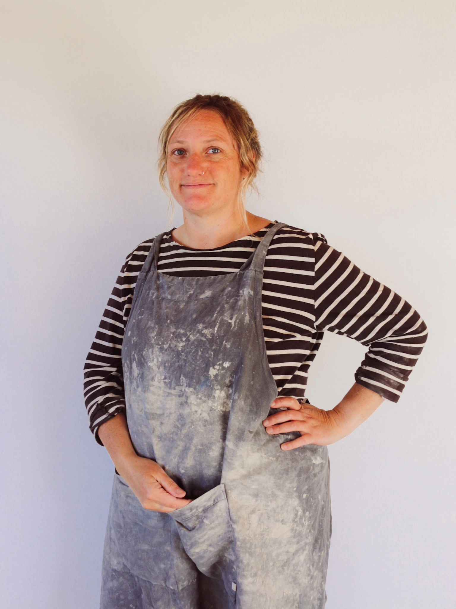 Laura Lane Ceramics wearing a studio apron covered in clay