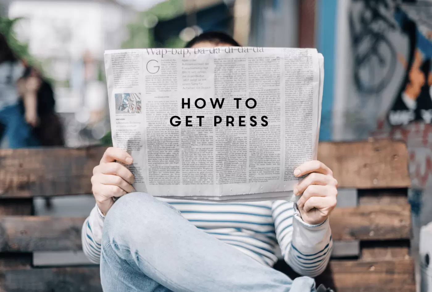 How to get press written on a newspaper being held by a person sat on a bench 