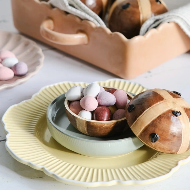 Wooden hot cross bun. A wooden hot cross bun which is split in half and open and filled with Easter eggs