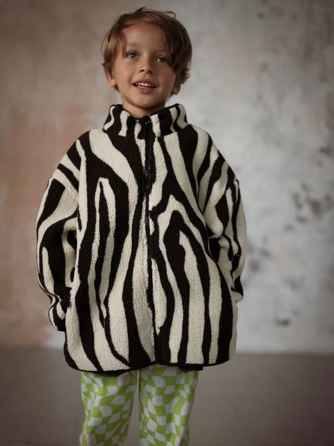 Child wearing Another Fox zebra fleece and green chequered trousers.