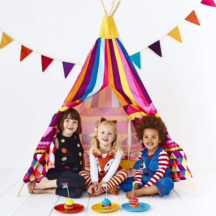 Wild Things brand image . children wearing play clothes against a teepee on white background