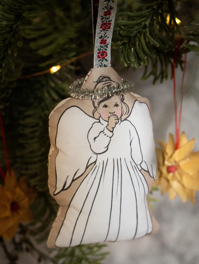 angel Christmas plush hanging on Christmas tree branch with pretty ribbon