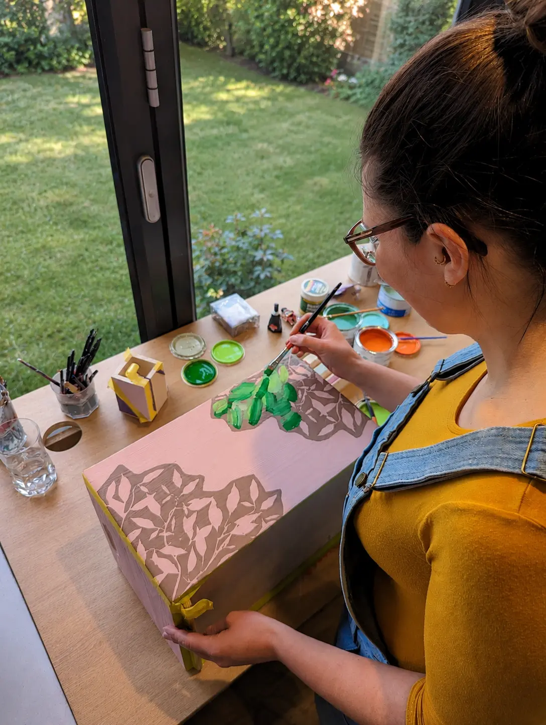 Artist hand-painting a personalised wooden keepsake box in a home studio.