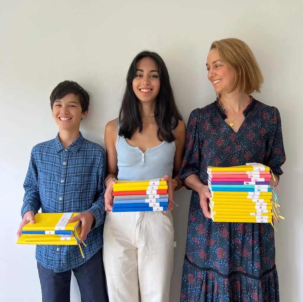 HappySelf Founder, Francesca, poses with her two children holding copies of the journal