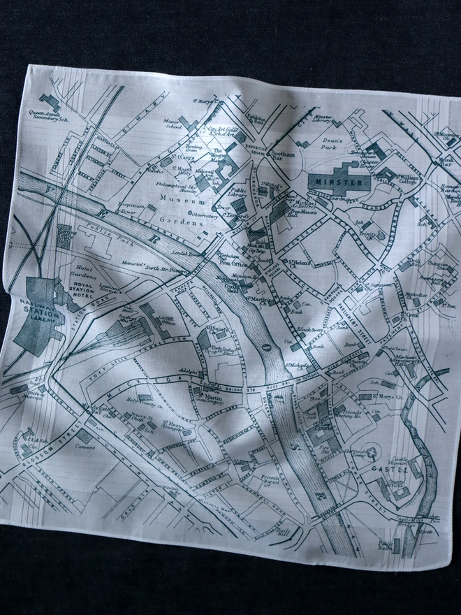 Mr.PS York map handkerchief printed in dark teal blue, laid on a dark background