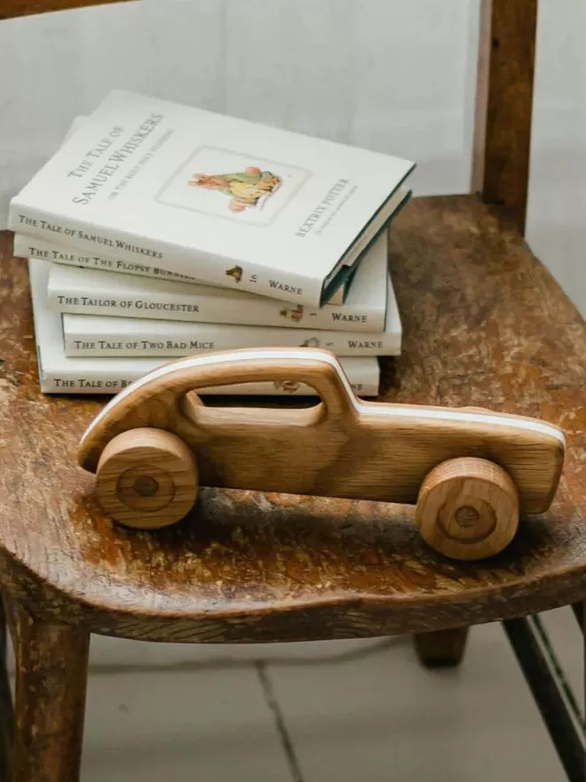 wooden toy car on a wooden car with books stacked behind 
