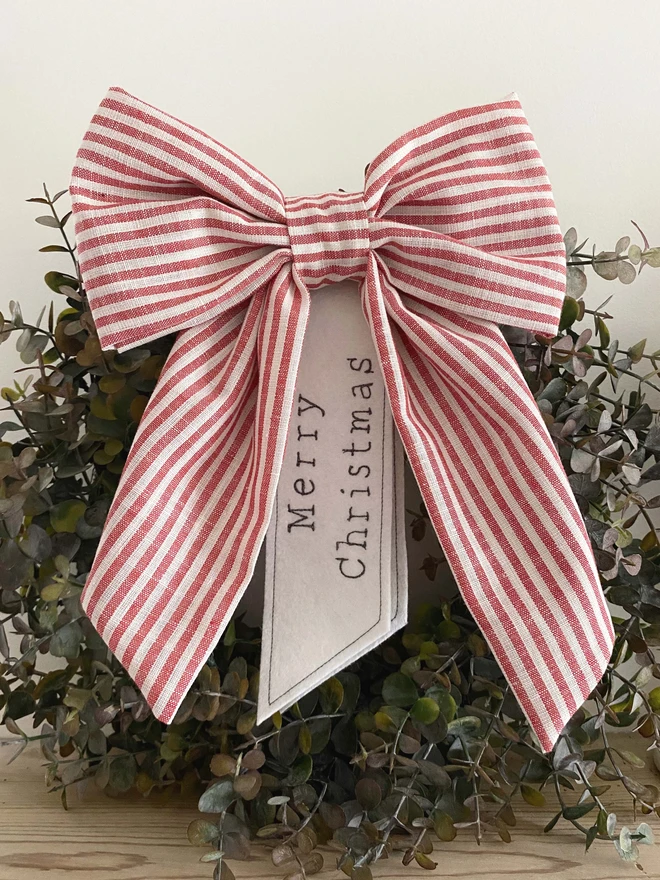 red stripe christmas bow on wreath with Merry Christmas words