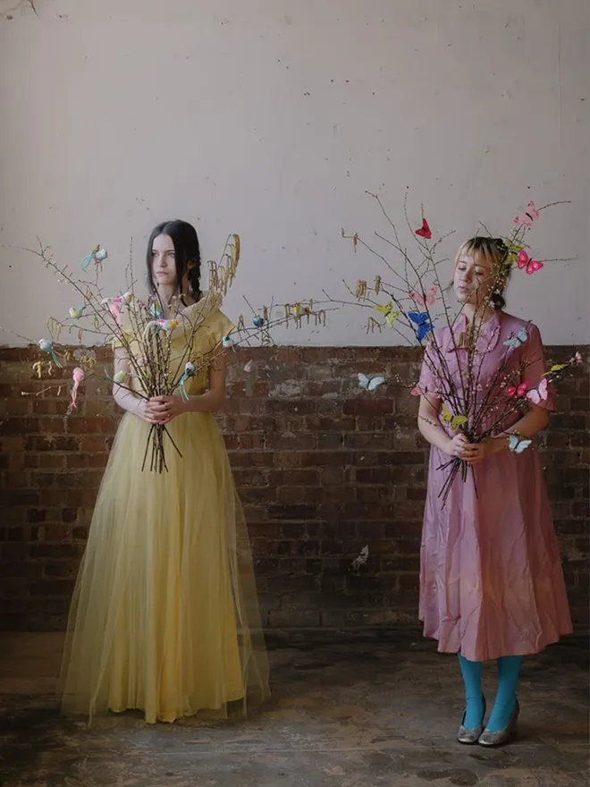 Bird and butterfly clips on blossom display bouquets held by girls in vintage dresses.