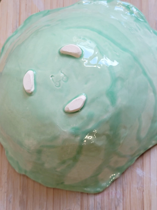 green glazed ceramic bowl on a wooden board showing the underside 