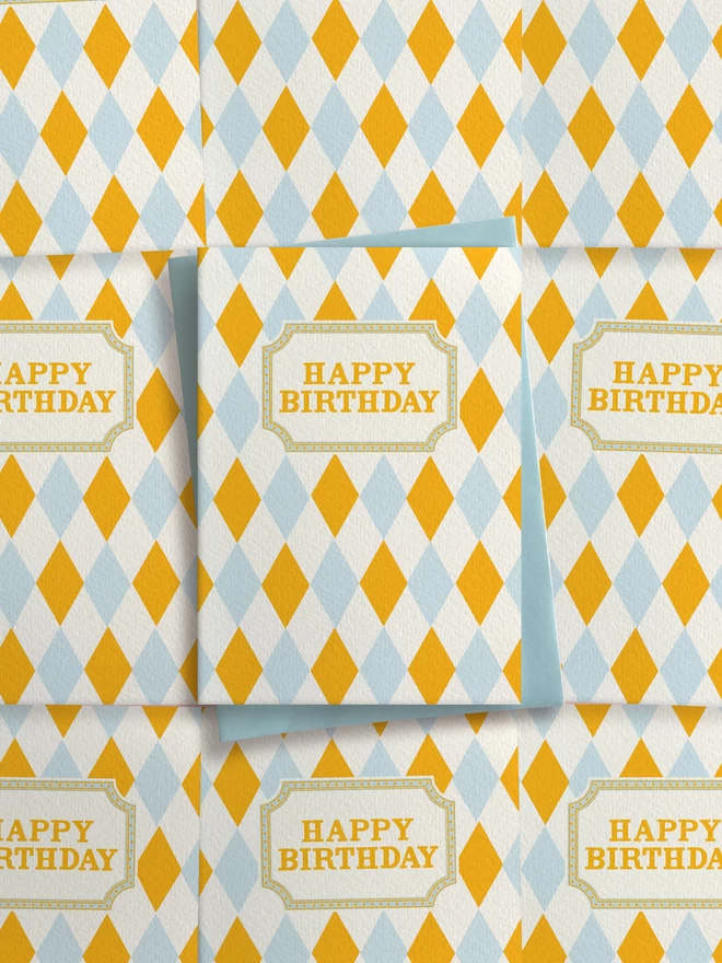 Greeting card designed by Flora Fricker in Bristol, UK. Happy Birthday harlequin pattern in yellow and blue. Gender neutral birthday card