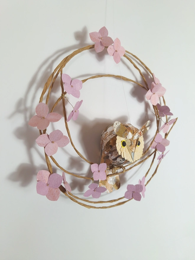 handmade paper sculpture of a long eared owl baby on a spring wreath of pink hydrangea flowers