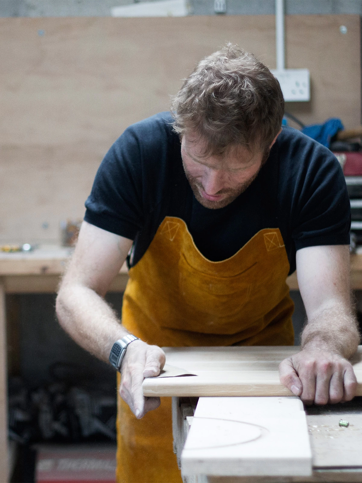 dave jones of coast creative in the workshop finish sanding a tabletop by hand