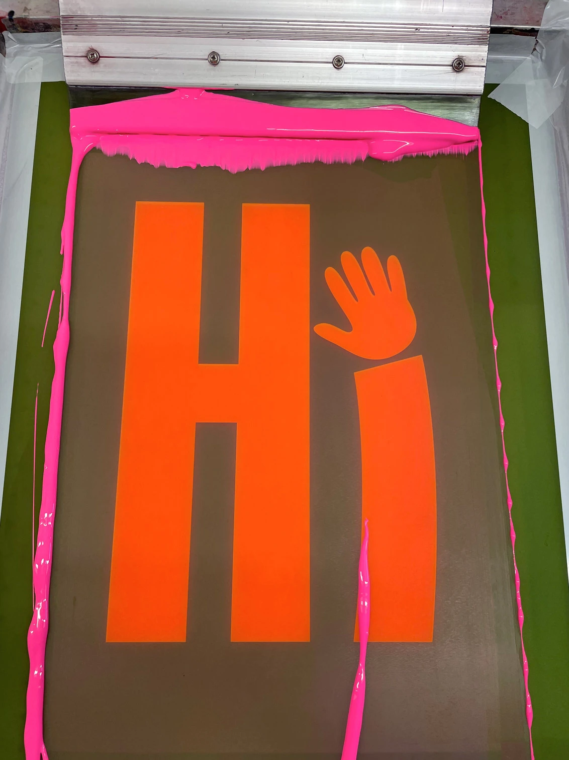 Screen printing screen with imahe of Hi with i being a waving hand the screen has pink ink on it