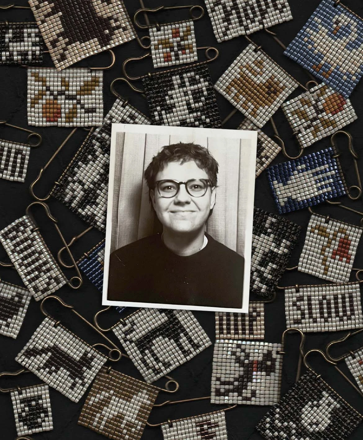 A black and white photobooth strip of a person with short, dark hair and glasses rests on top of a collection of beaded brooches