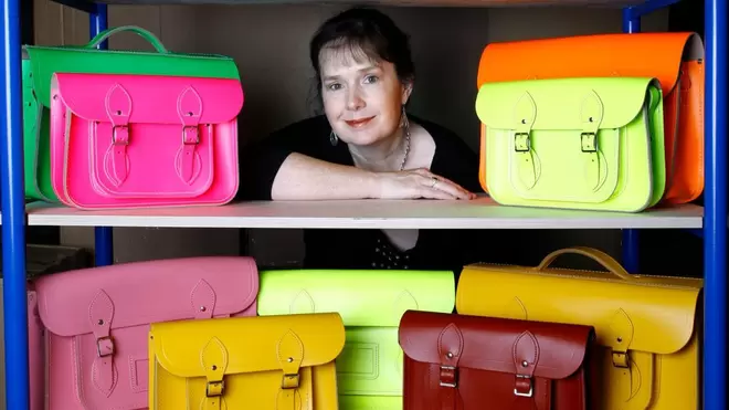 Julie Deane CBE, founder of the Cambridge Satchel Company, surrounded by satchels