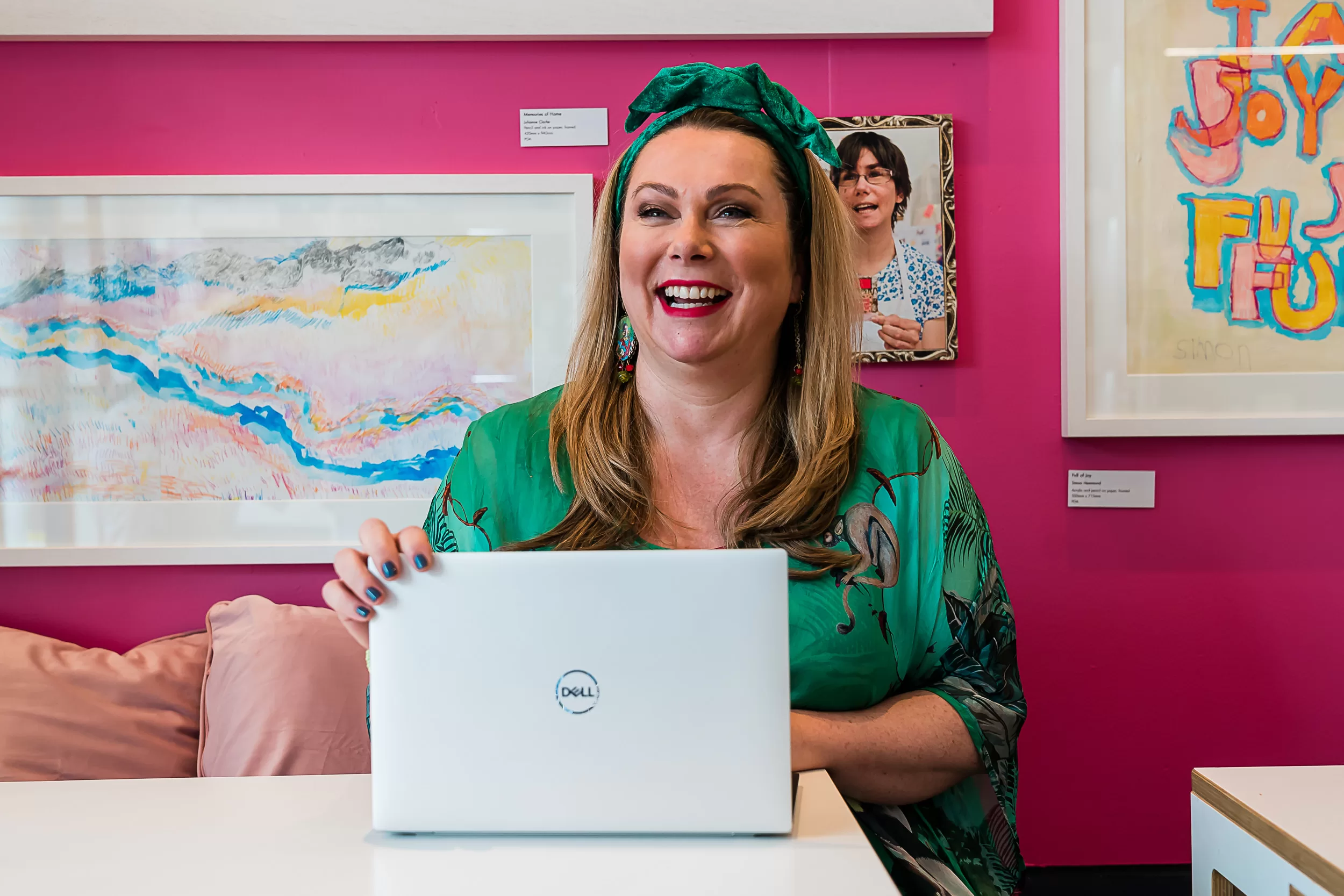 Holly Tucker MBE smiling past the camera with a Dell Laptop in the Holly & Co Workshop