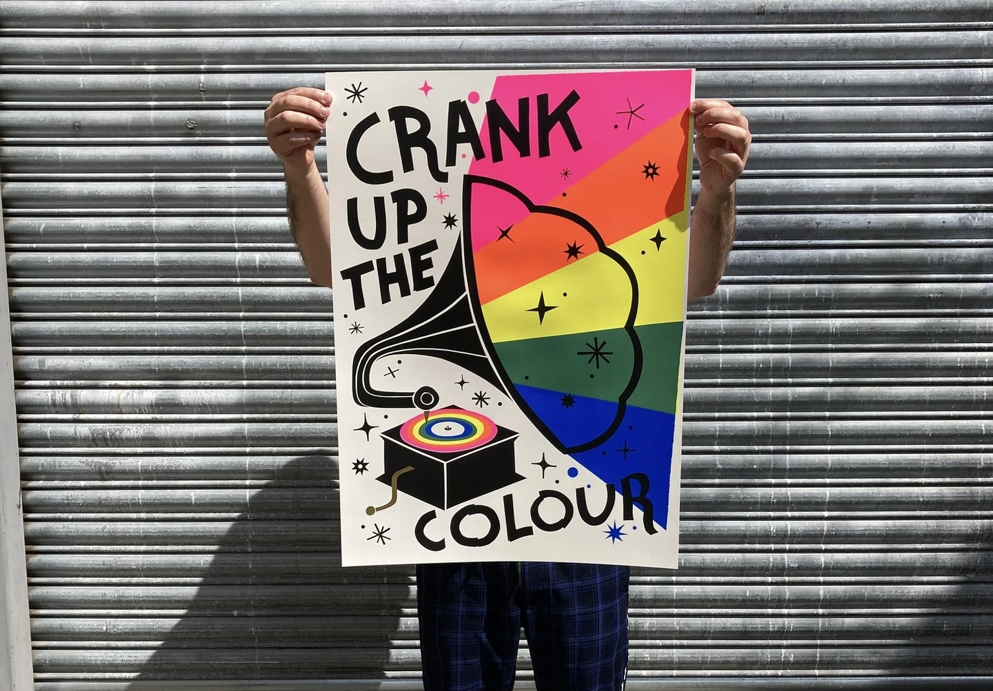 Crank up the colour print. A megaphone speaker with bright colours coming out of it with the words crank up the colour around