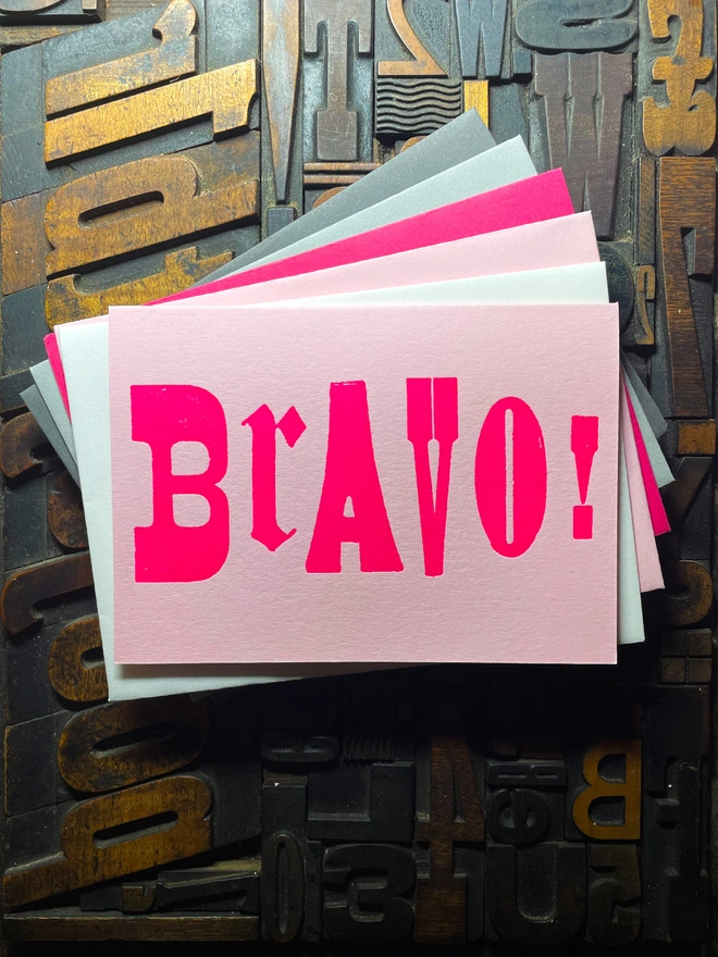 A congratulatory letterpress candy pink card featuring the deep impression word BRAVO!; in bold letters with a set of colourful envelopes. Perfect for exam results and graduations and other celebrations and milestones.