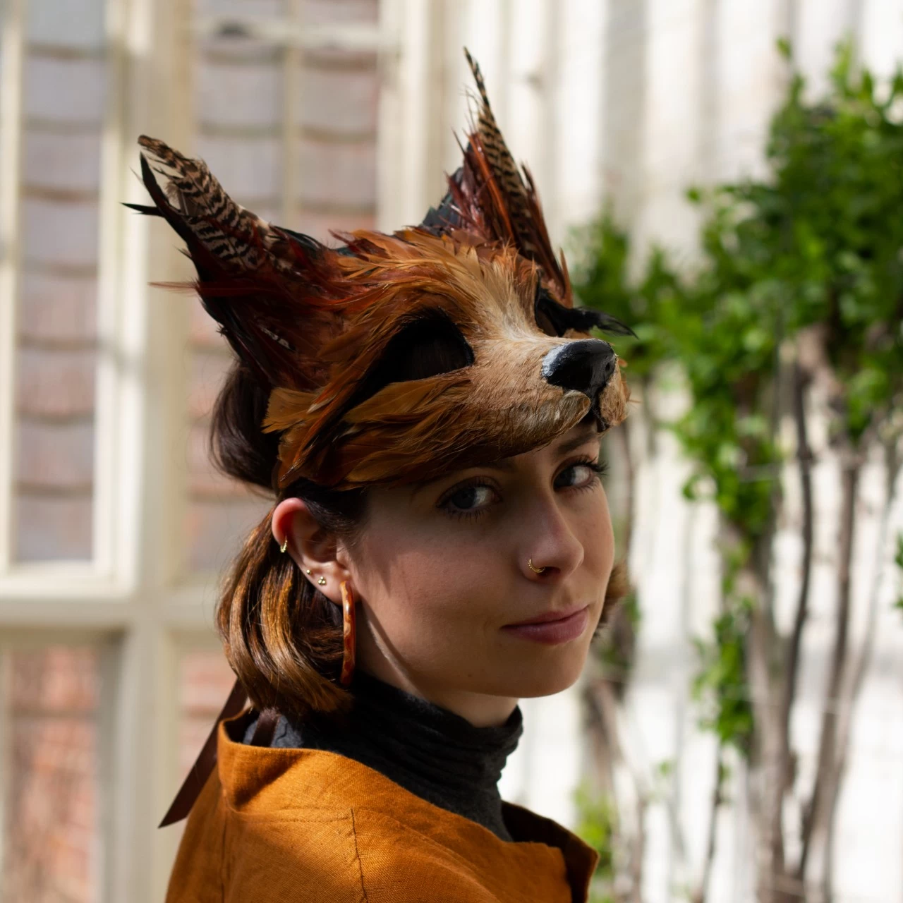 A woman wearing a luxury red fox masquerade party mask in a garden