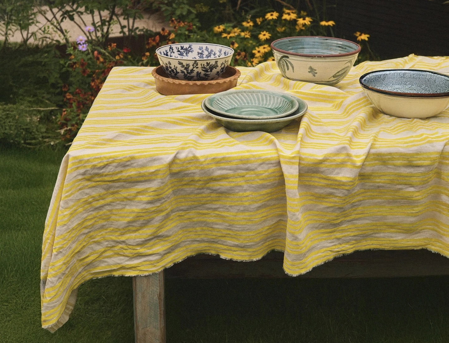 Yellow hand block printed striped tablecloth. A lemon yellow striped tablecloth on a long table with ceramic serving platters on top