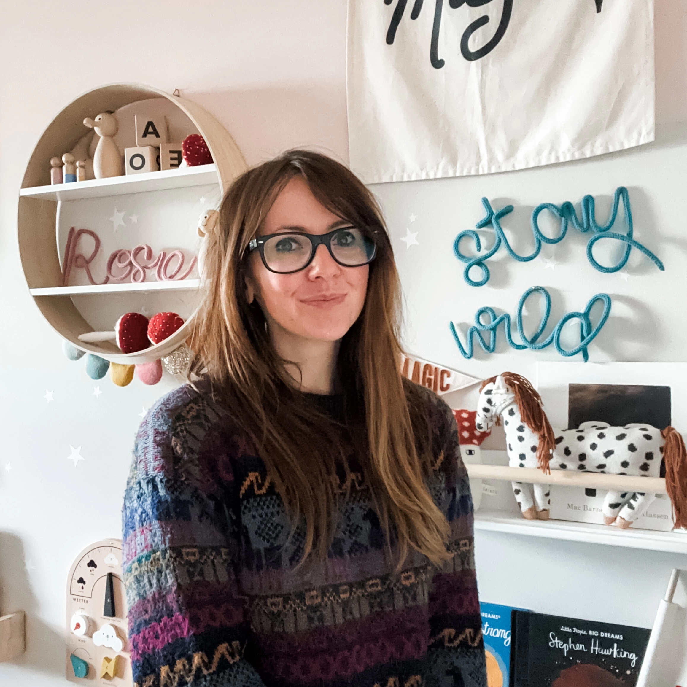 Marti, owner of heykiddostudio, in the studio infront go a wall full of kids nursery decor