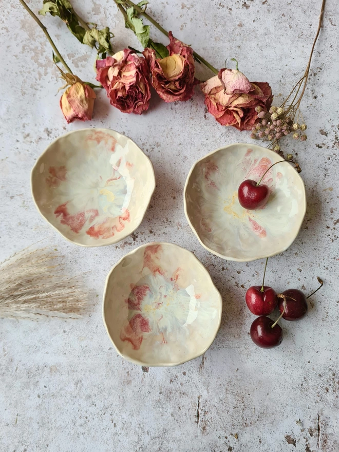 Triple mini ceramic bowls, pottery bowls, gifts, homeware, tableware, dip bowl, snack bowl, small bowl, Jenny Hopps Pottery, Dream Catcher, white cream, neutrals, photographed with dried flowers, cherries on a mottled white background, and pink