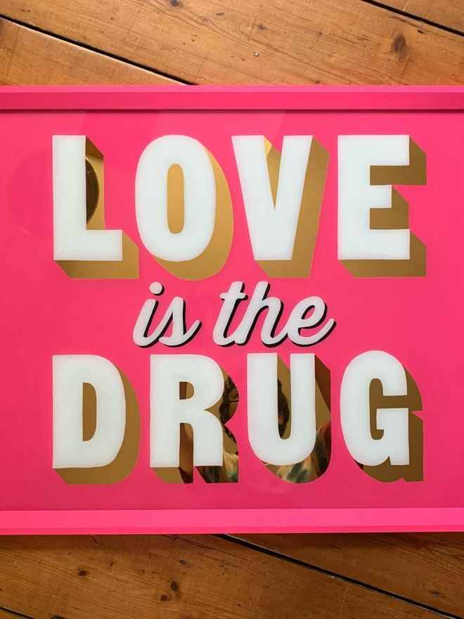 pink and gold love is the drug sign
