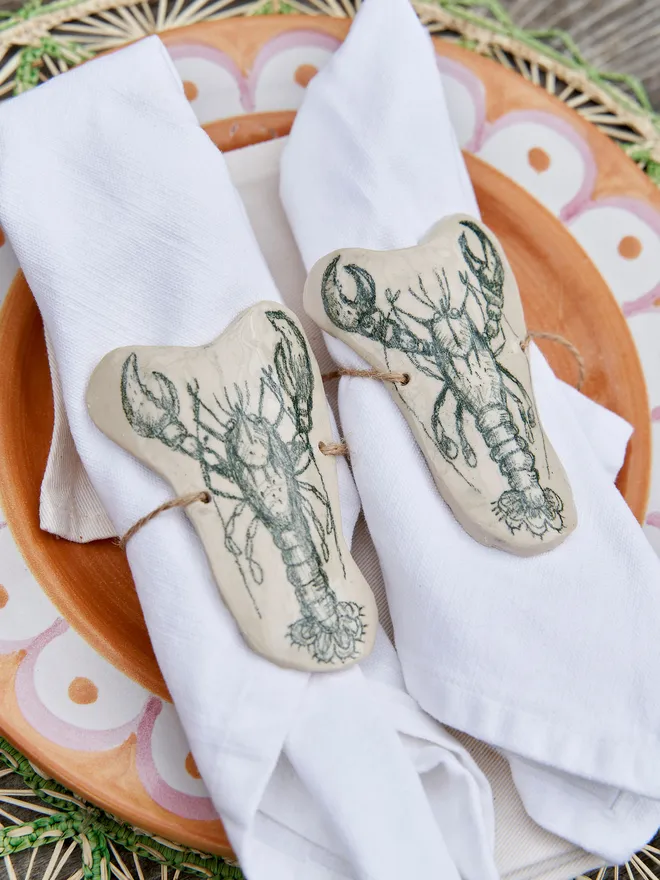 Ceramic Lobster Napkin Ring Holder, a ceramic lobster napkin sitting on a wicker placemat. 