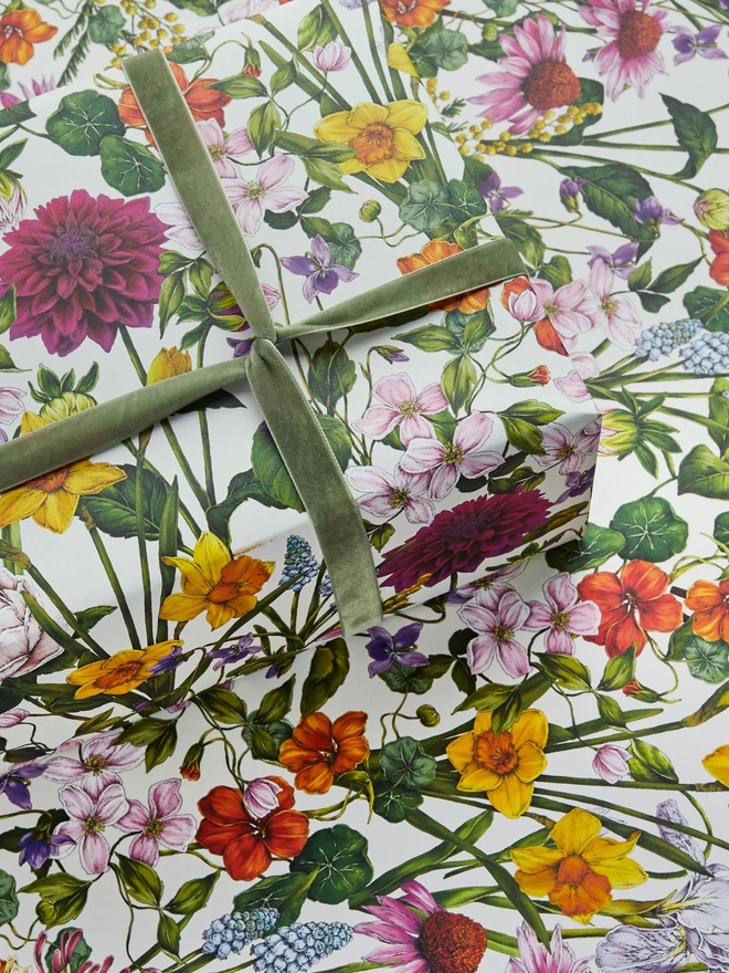 bountiful blooms floral gift wrap sheet. a box wrapped in multi-coloured illustrated floral gift wrap with a green ribbon.