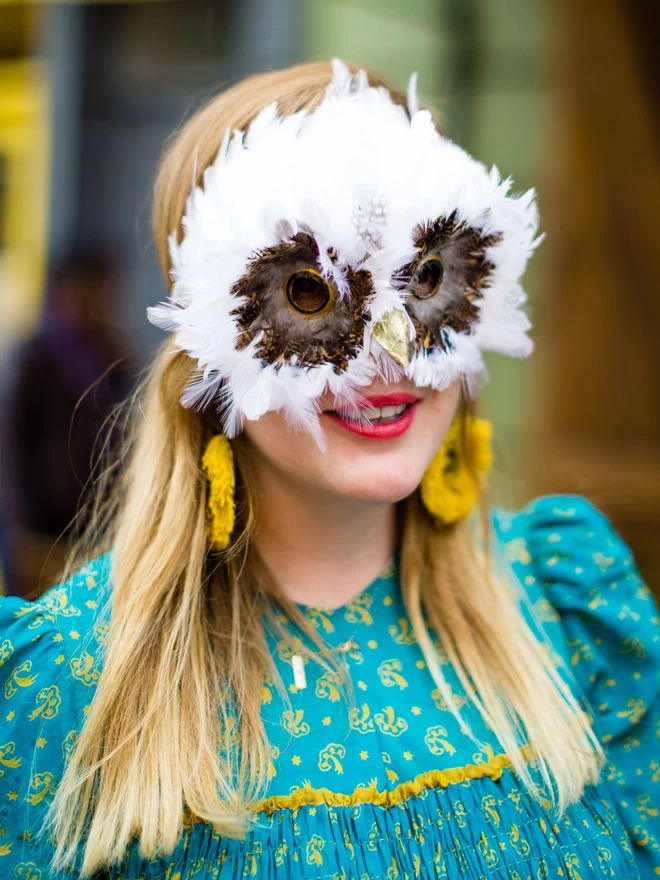 Woman wearing luxury white owl party mask down over her face