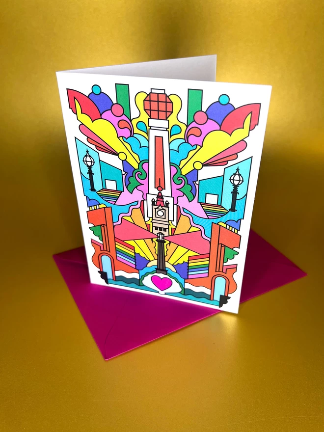 A greetings card of black line drawing with rainbow colours depicting Margate landmarks, sits on top of a pink envelope on a gold backdrop.