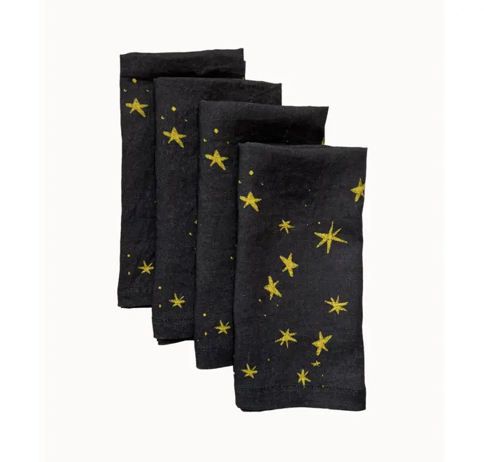 Stars Napkins In White (Set of 4). Set of four blue  cloth napkins with scattered yellow star prints, stacked in a staggered arrangement.